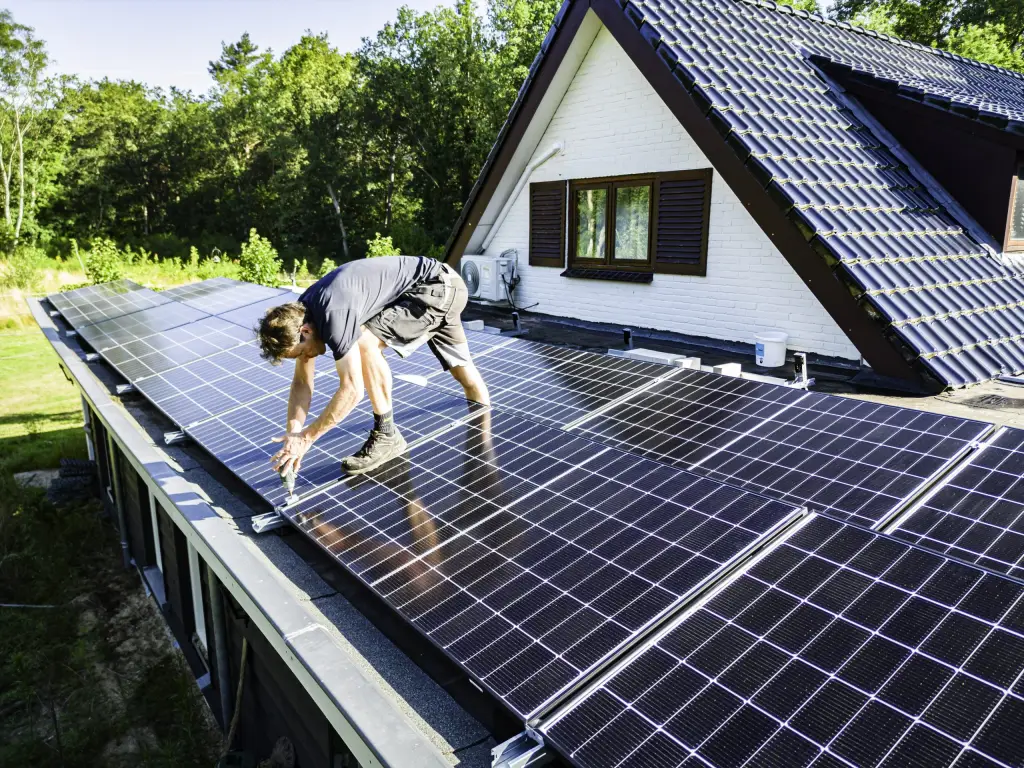 Monteur monteert een zonnepaneel op een plat dak