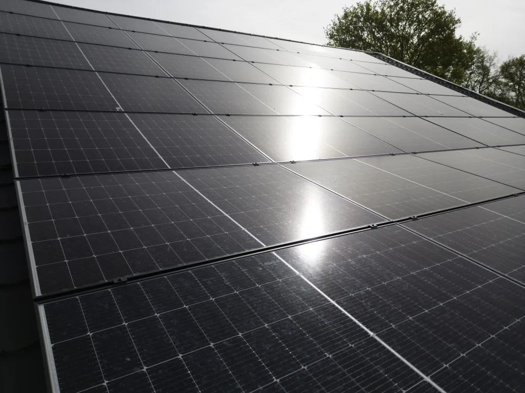 Zonnepanelen op een dak met de zon erin weerspiegeld