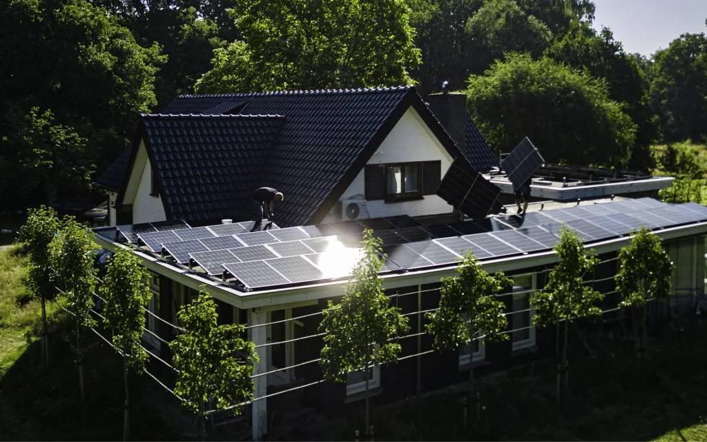 Monteurs leggen zonnepanelen op het platte dak van een vrijstaande woning