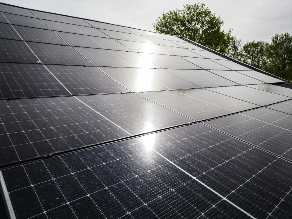 Zonnepanelen op een schuin dak met de zon erin weerspiegeld