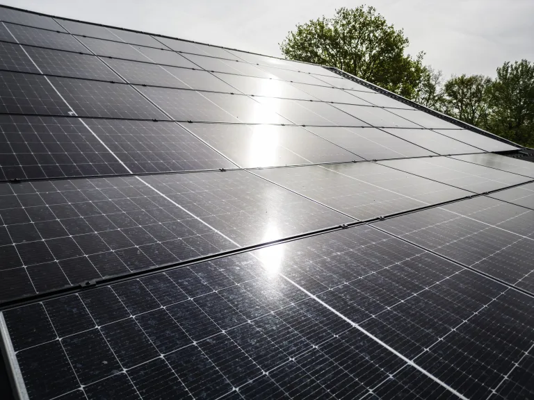 Zonnepanelen op een schuin dak met de zon erin weerspiegeld